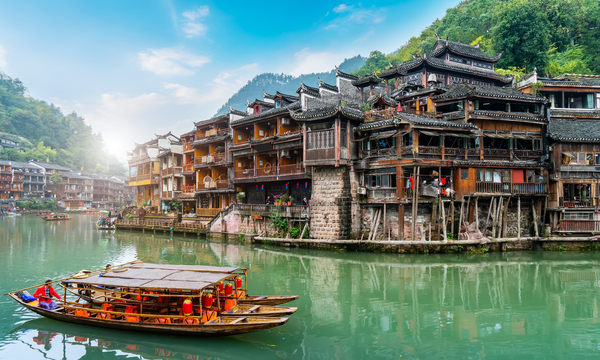 Umgeben von überwucherten Bergen und durchzogen vom Bergfluss Tuojiang, krallen sich mehrstöckige hölzerne Pfahlbauten an die Uferseiten der antiken Stadt Fenghuang aus der Zeit der Qing-Dynastie.