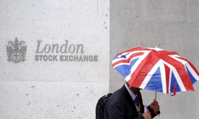 File photo of a worker sheltering from the rain as he passes the London Stock Exchange in the City of London