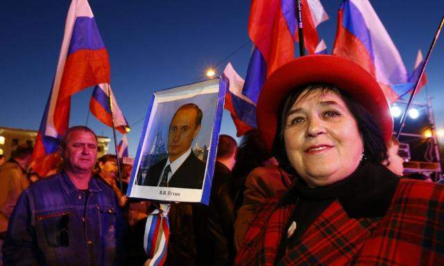 A woman holds a portrait of Russia's President Vladimir Putin during celebrations on the main square of the Crimean city of Simferopol
