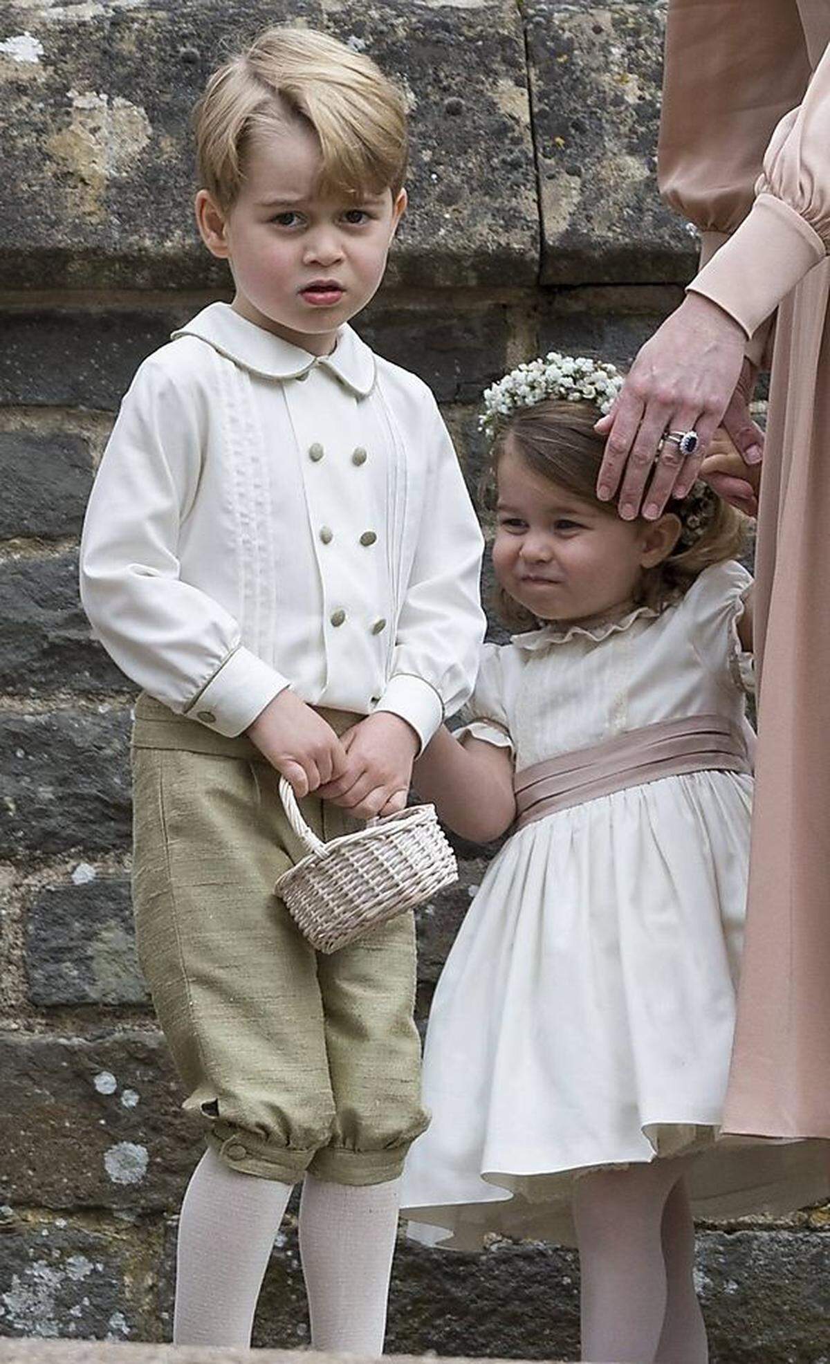 So wirklich glücklich schienen Prinz George und Schwester Prinzessin Charlotte in ihren extra angefertigten Blumenkinder-Outfits der Londoner Kindermodemarke Pepa &amp; Co. nicht zu sein. Die Buben trugen grün-goldene Hosen, die Mädchen gefütterte Kleider mit rosafarbenen Schleifen und Blumenkränze.