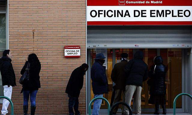 People wait in line to enter a government-run employment office in Madrid