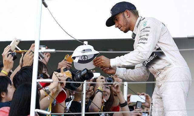 Lewis Hamilton signiert eine Kappe.