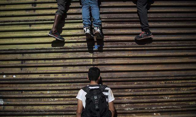 Migranten kletterten auf einen Blechwall, der noch auf mexikanischem Gebiet vor der US-Grenzmauer steht