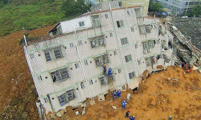 Rettungsarbeiter klettern auf ein verschüttetes Gebäude.