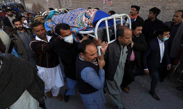 Männer tragen den Leichnam eines der beiden getöteten Priester in Peshawar.