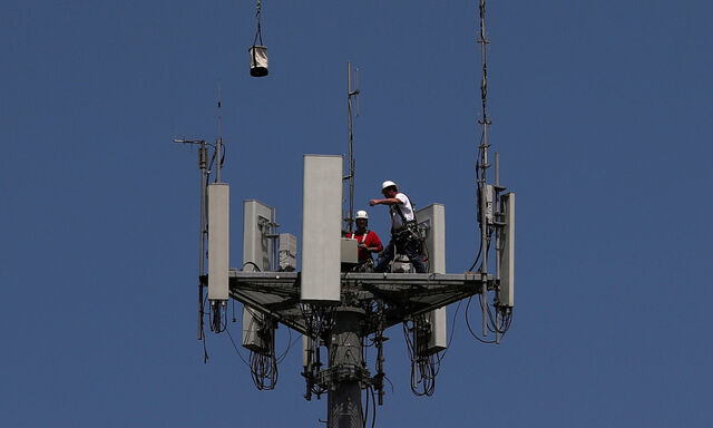 FILE PHOTO: Workers install 5G telecommunications equipment on a T-Mobile tower in Seabrook, Texas
