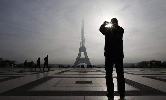 A tourist takes a picture of the Eiffel tower as he visits the Trocadero square in Paris