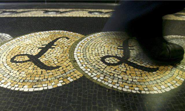 File photograph shows an employee walking over a mosaic depicting pound sterling symbols on the floor of the front hall of the Bank of England in London
