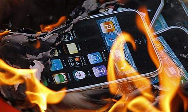 Protesters burn pieces of paper in the shape of iPhones, manufactured by Foxconn, during a demonstrat