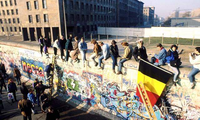 Berliner sitzen auf der Mauer nach der Wiedervereinigung in Berlin