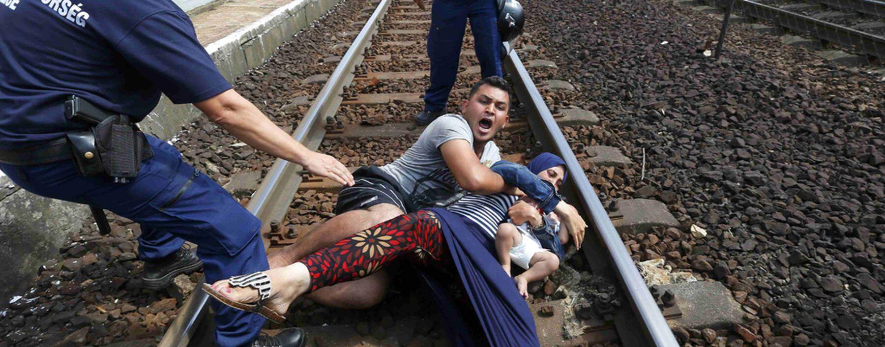 Hungarian policemen stand by the family of migrants as they wanted to run away at the railway station in the town of Bicske