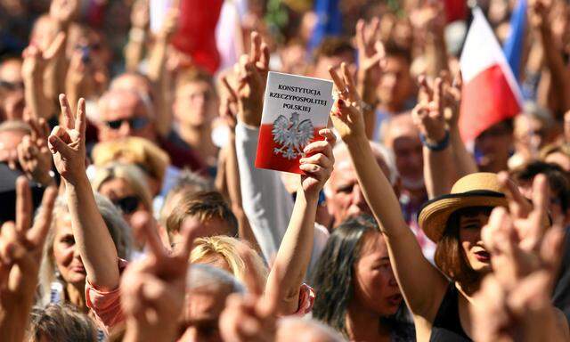 A protester holds a copy of the Polish Constitution during an opposition protest at the Market Square in Krakow