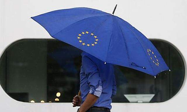 A person with an umbrella featuring the symbol of the European Union walks towards the interim facility of Germany's high constitutional court  in Karlsruhe