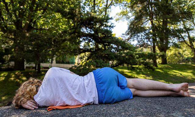 A young man naps in the shade during hot weather in Portland