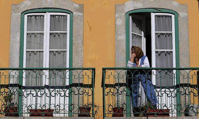 A woman watches a demonstration against government policies from her balcony in Lisbon