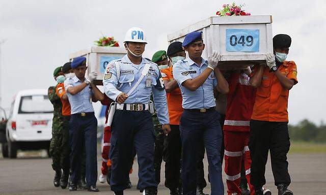 Indonesische Soldaten und Helfer tragen die Särge der bisher geborgenen Absturz-Opfer.