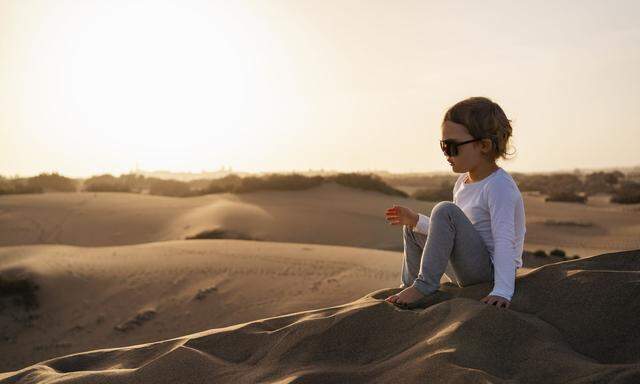 Girl sitting in sand dunes, Gran Canaria, Spain