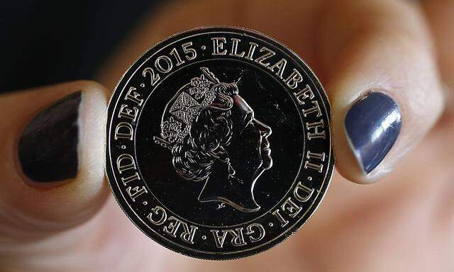 A gallery assistant poses with a 2-pound coin with the new portrait of Britain´s Queen Elizabeth following it´s unveiling at the National Portrait Gallery in London