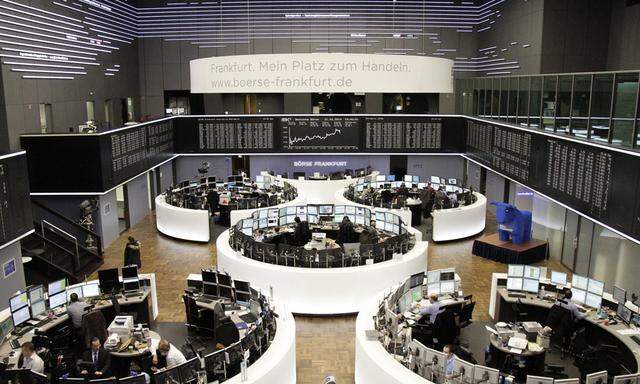 Traders are pictured at their desks in front of the DAX board at the Frankfurt stock exchange