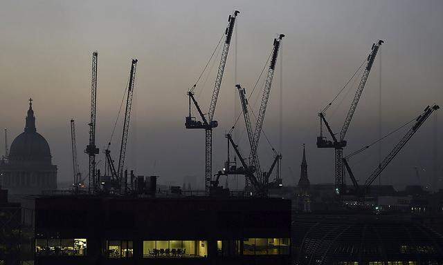 Offices are seen at dusk as St. Paul's cathedral and construction cranes are seen on the skyline in the City of London