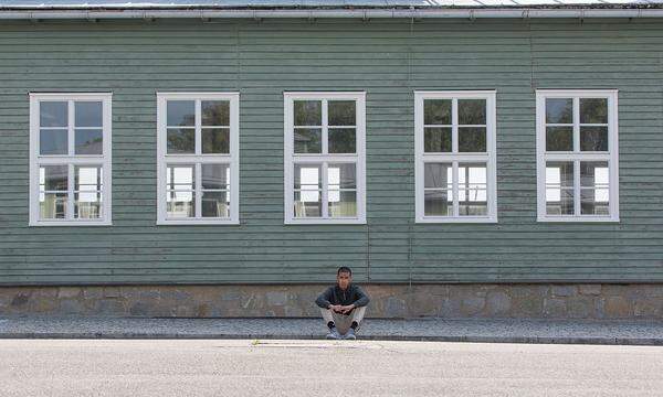 Ein muslimischer Jugendlicher sitzt am ehemaligen Appellplatz im Schatten einer der noch wenigen erhaltenen Barracken.