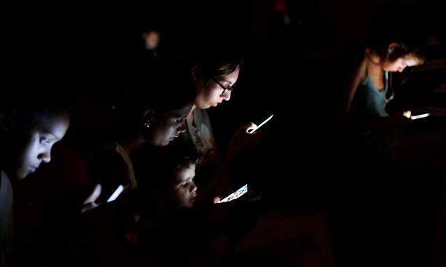 People surf the internet on their mobile devices at a hotspot in Havana, Cuba