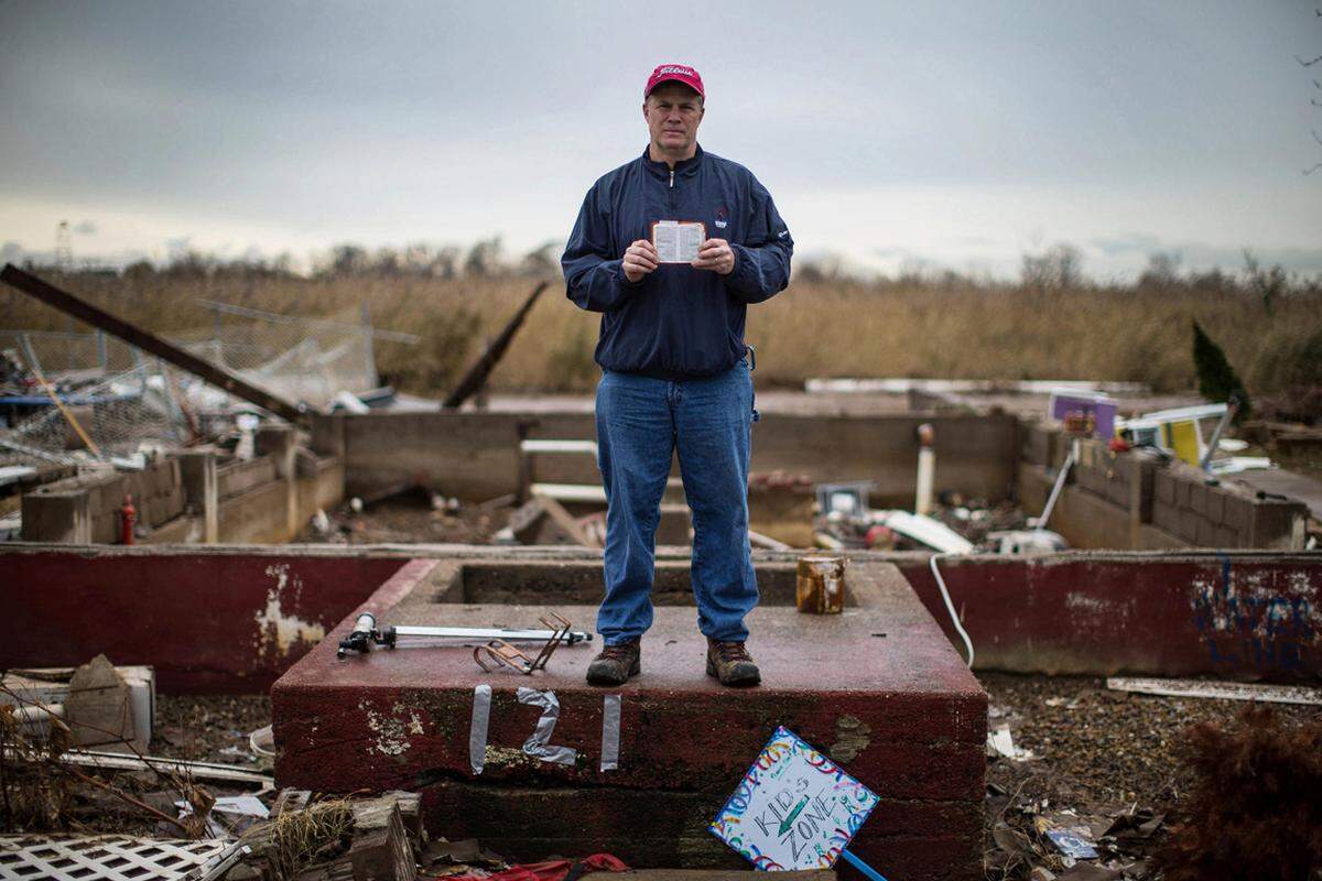 Pastor Joseph Paul Morrissey hält seine Taschenbibel vor den Ruinen seines Hauses in Oakwood, Staten Island, in die Kamera. Nicht weit weg steht seine "Grace Bible Church", die er gemeinsam mit seinen Gemeindemitgliedern zu einem Hilfszentrum für Strumopfer gemacht hat, obwohl sie alle vor den Ruinen ihrer Existenz stehen.