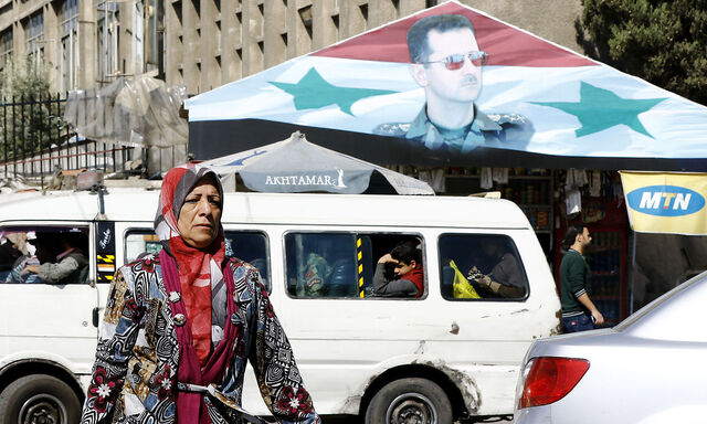 Eine Frau vor einem Assad-Banner in Damaskus.