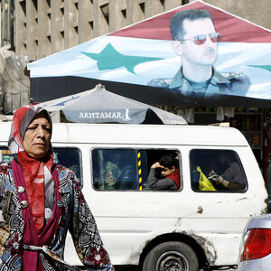 Eine Frau vor einem Assad-Banner in Damaskus.