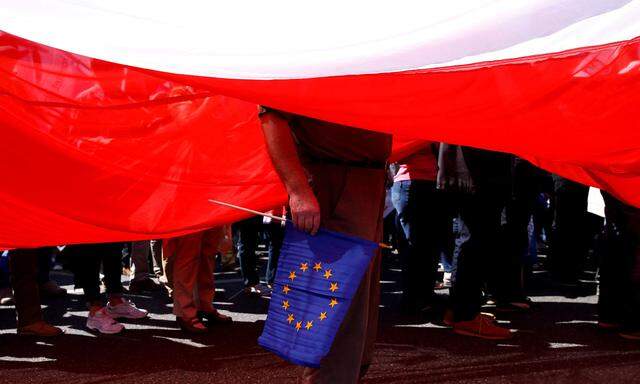 Ein Demonstrant steht mit der EU-Flagge unter einer riesigen weiß-roten Fahne Polens. 