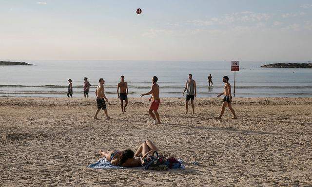 FILE PHOTO: Men play with a ball as they enjoy unusual warm weather on a beach in Tel Aviv