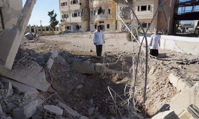 A doctor accompanied by a nurse inspect a crater caused by what activists said were barrel bombs dropped by forces loyal to Syria's President Bashar al-Assad on a hospital in the city of Nawa, in Deraa province