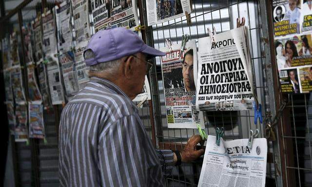 A man reads a newspaper front page bearing a picture of Greek PM Tsipras in Athens