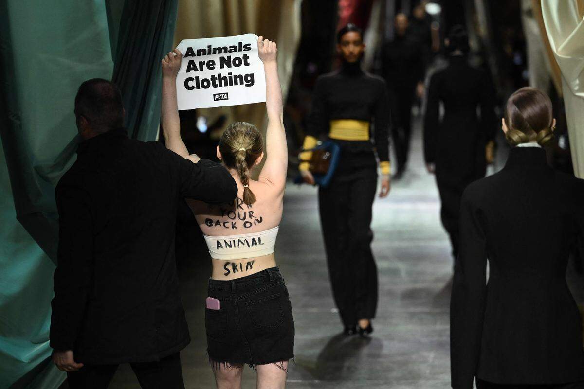 21. Februar. Ein Sicherheitsbeamter hält eine Frau auf, die ein Plakat mit der Aufschrift „Tiere sind keine Kleidung“ während der Fendi-Kollektionsschau auf der Mailänder Modewoche hält.