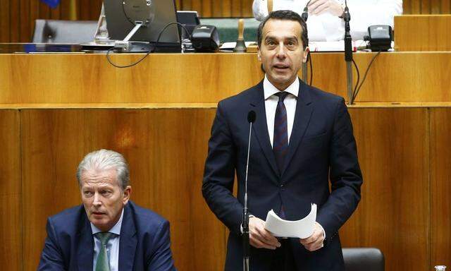 Austria's Chancellor Kern stands next to Vice Chancellor Reinhold Mitterlehner as he delivers a speech in the parliament in Vienna
