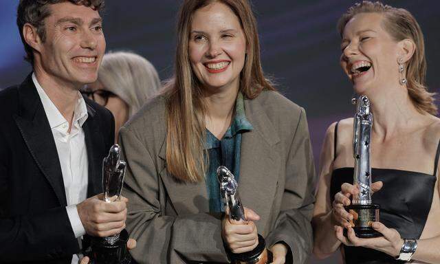 Regisseur Justine Triet, Schauspielerin Sandra Hueller und ein Crew-MItglied mit ihren Trophäen für „beste Regie“, „bestes Drehbuch“ und „beste Schauspielerin“.