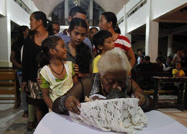 Philippinische Taifun-Opfer küssen die Christusfigur einer Kirche in Palo.