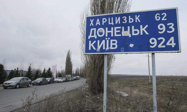 Cars queue to reach a border crossing point, before driving into Russian territory, outside the village of Uspenka