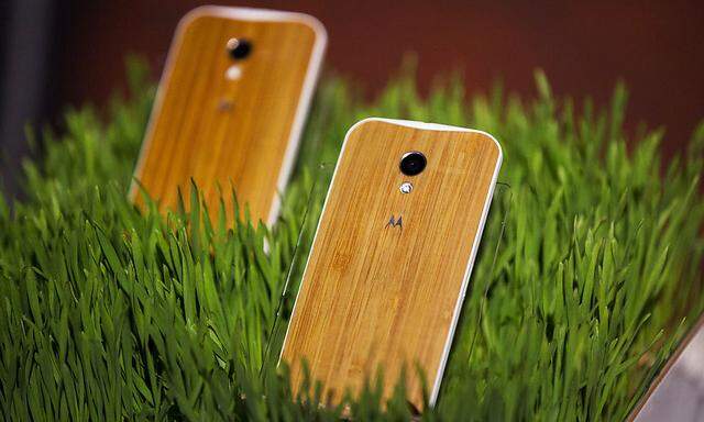 Phones with wooden backs on them rest in a display at a launch event for Motorola´s new Moto X phone in New York