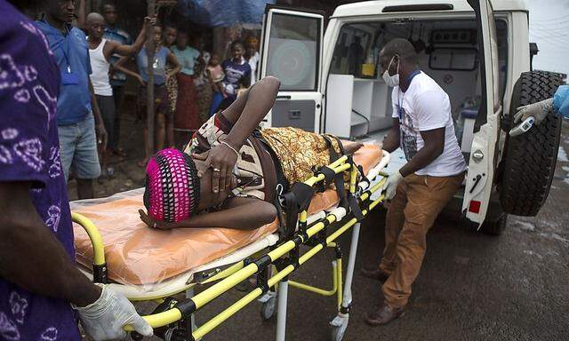 A pregnant woman suspected of contracting Ebola is lifted by stretcher into an ambulance in Freetown