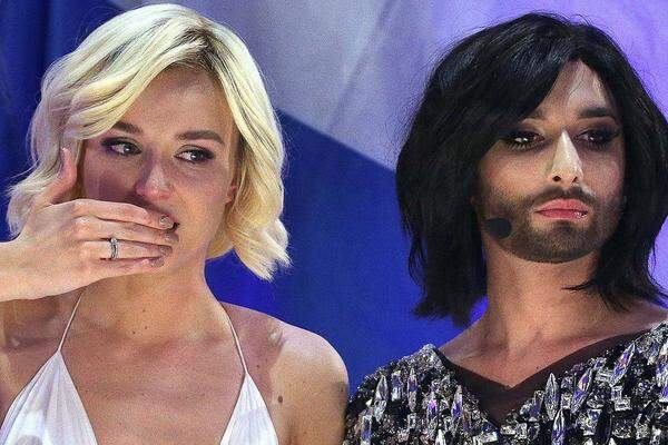 Einer der Bilder des Abends: Immer mehr Buh-Rufe ereilen Polina Gagarina aus Russland, wenn zwölf Punkte für ihr Land erteilt werden - unverdient. Und dann dieses Bild: Gagarina sitzt mit Conchita Wurst auf der Couch im Green Room - einem schwulen Mann in Frauenkleidern mit Bart - live im russischen Fernsehen.