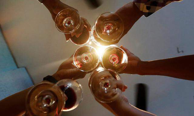 Men toast with their glasses of wine at a restaurant in Phnom Penh