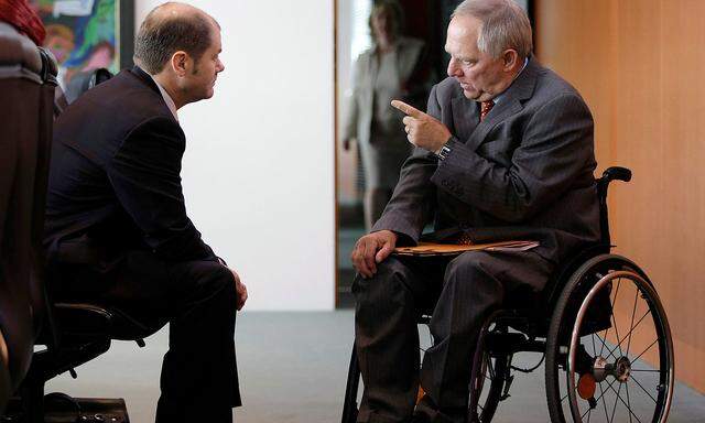 FILE PHOTO: German Labour Minister Scholz and Interior Minister Schaeuble talk before the weekly cabinet meeting in Berlin