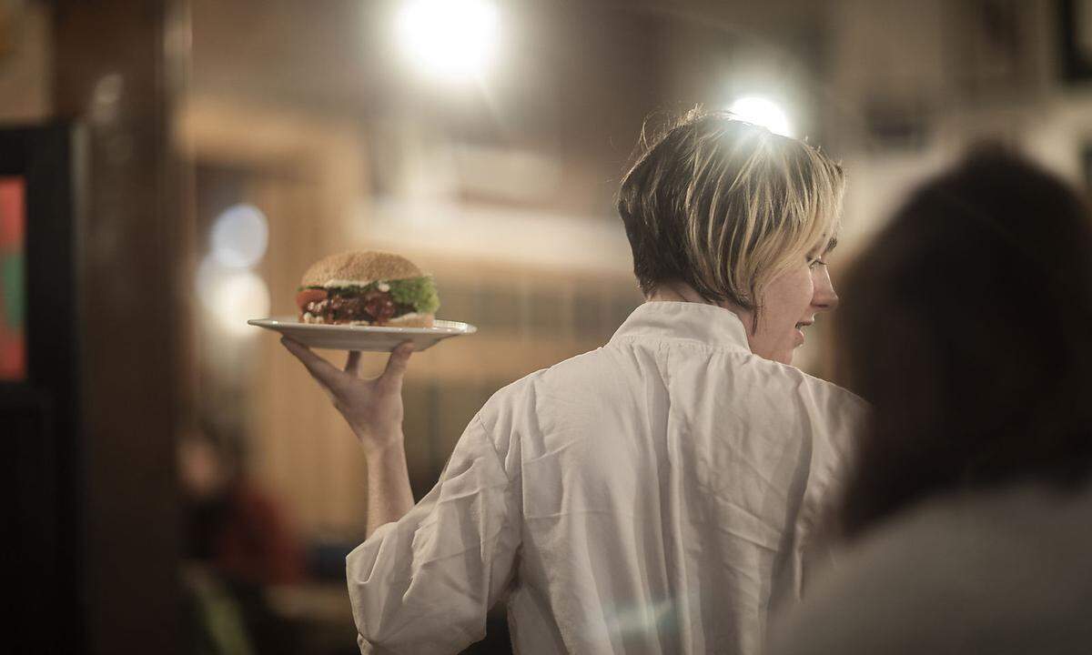 Waitress serving plate of burger in gastro pub