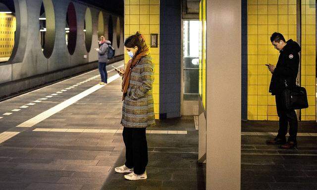 Netherlands, Rotterdam. 4 January 2022. Train passengers wait for their train while using their mobile phones at Blaak s