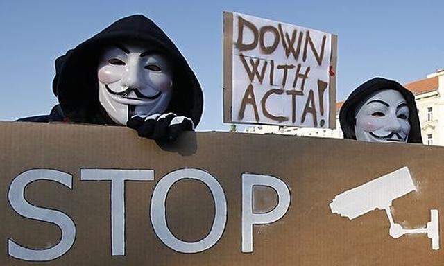Protesters wearing Guy Fawkes masks hold a banner during a demonstration against the Anti-Counterfeit