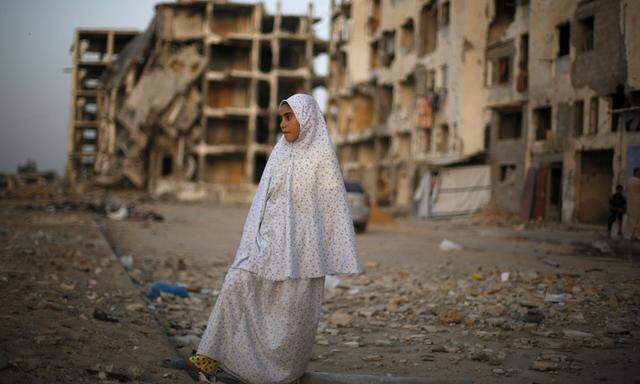 Palestinian girl stands near residential buildings that witnesses said were heavily damaged by Israeli shelling during a 50-day war last summer, in Beit Lahiya town in the northern Gaza Strip