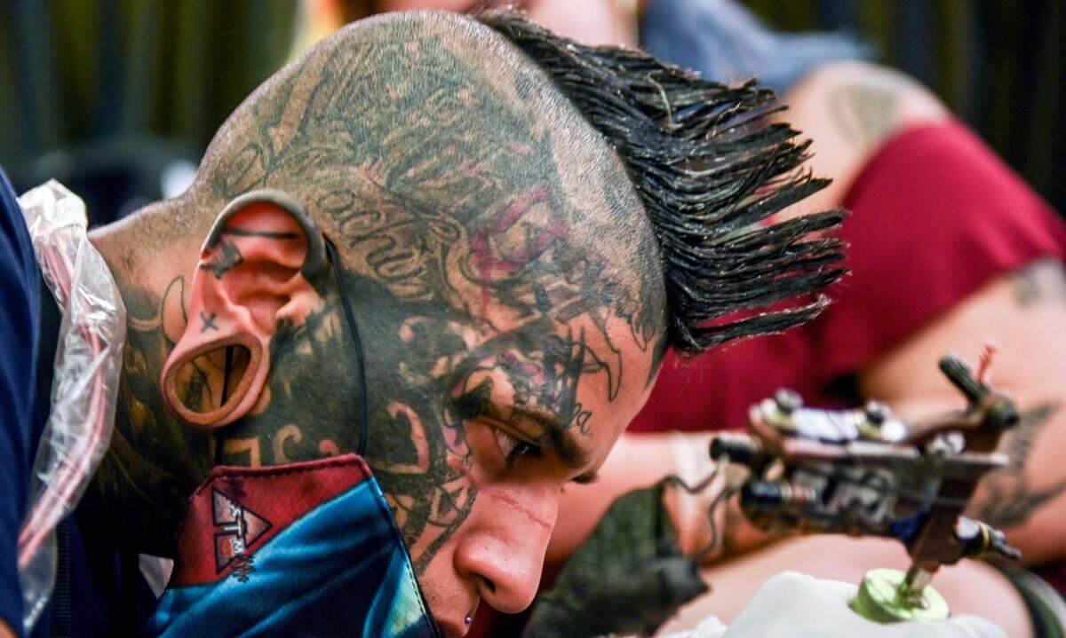 Ein Tattoo-Künstler bei der Arbeit bei der zehnten Colombia Fair in Medellin im Juni 2019.