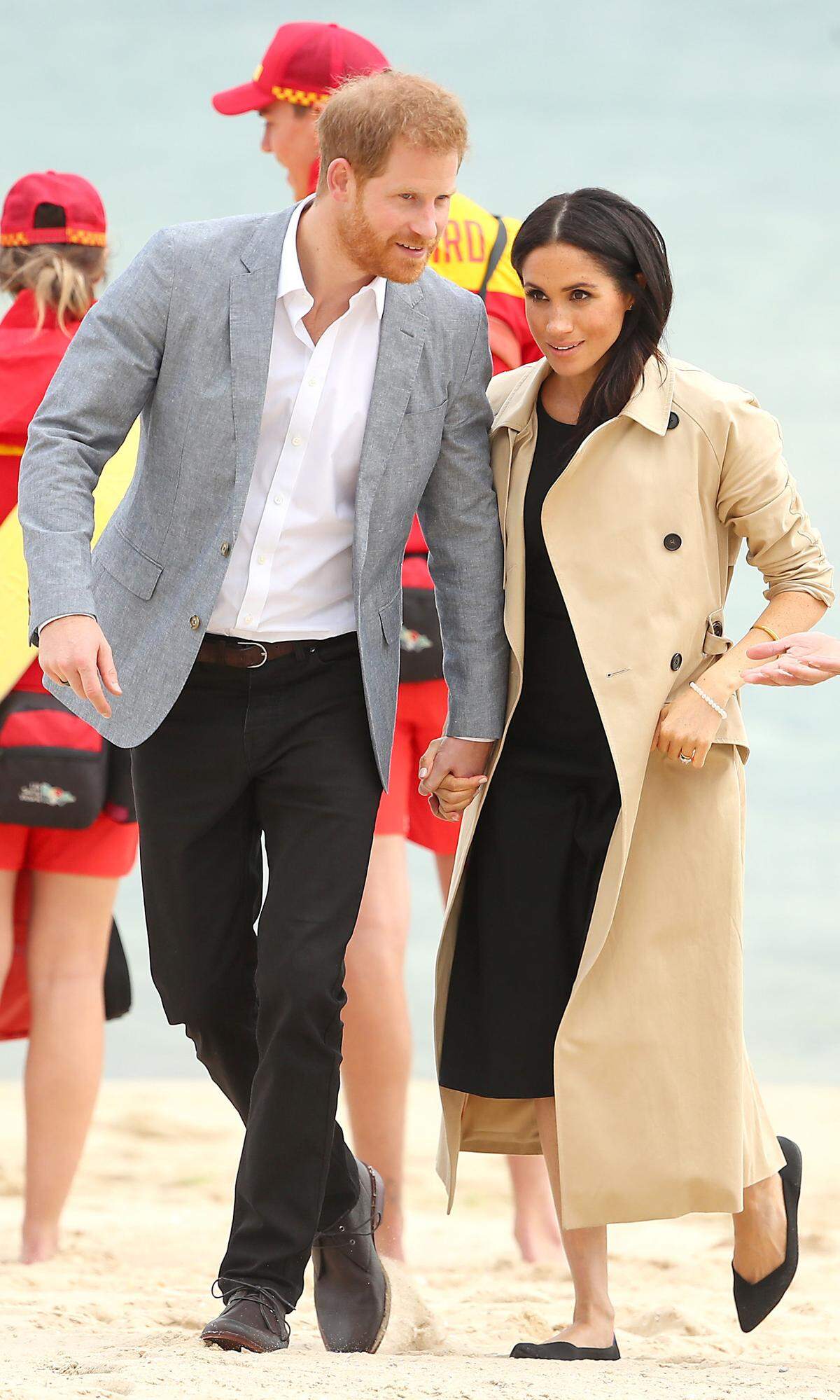 Noch brauchen die werdenden Eltern keine Sandburgen bauen - in diesen Outfit ohnehin keine gute Idee. Für einen Ausflug an den Strand von Melbourne schlüpfte Meghan in ein schwarzes Club Monaco "Miguelina" Kleid mit Knopfdetails am Rock und passende schwarze Ballerinas von Rothy - sehr umweltbewusst. Gegen die kühle Meeresbrise schützte ein beiger Trench Coat von Martin Grand.