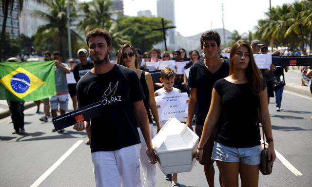 Members of the NGO Rio de Paz (Rio of Peace) attend the symbolic funeral of 10-year-old boy Eduardo de Jesus, who died last week during a shootout between policemen and drug dealers in Alemao slums complex, during a protest in Copacabana